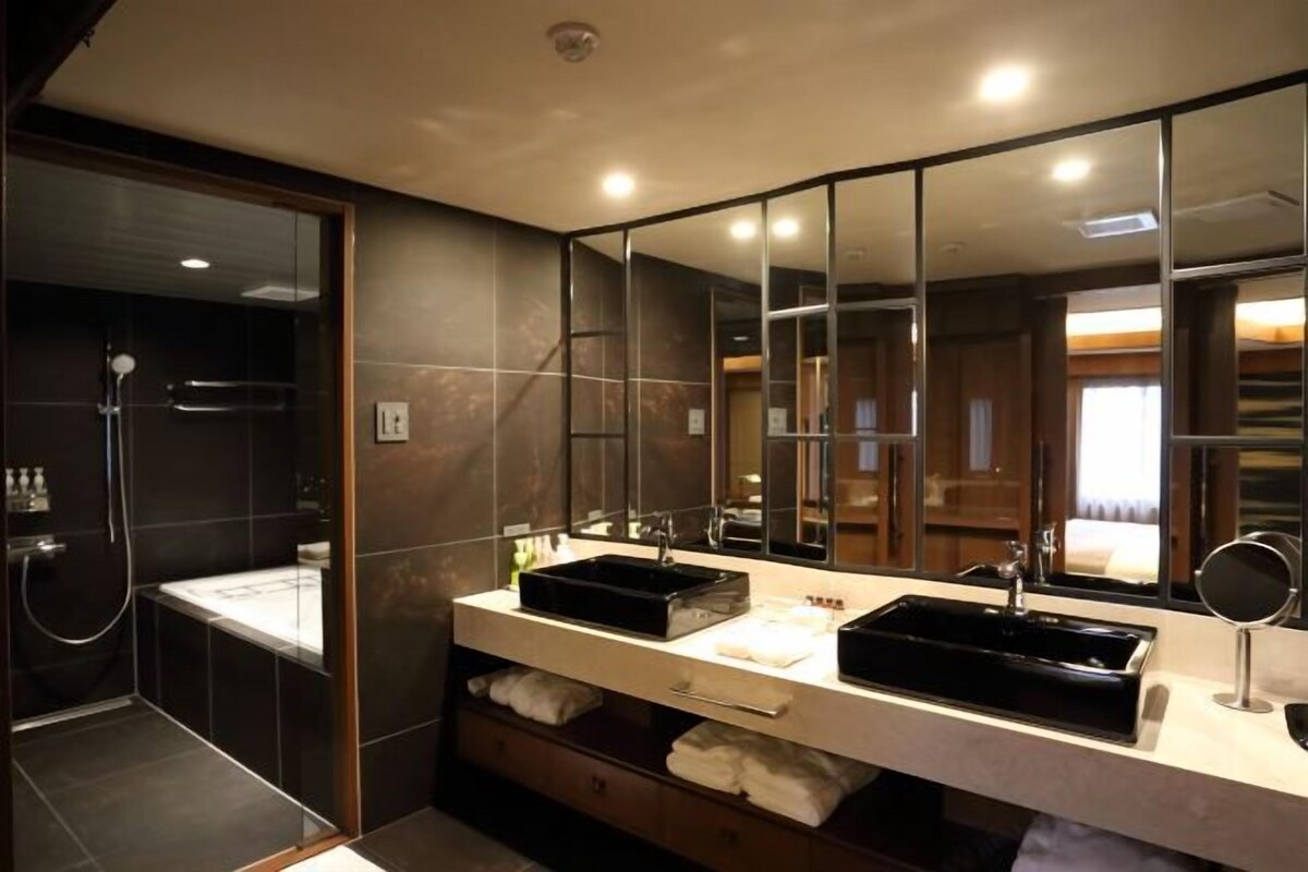 A modern bathroom with a double sink, large mirror, and a walk-in shower.