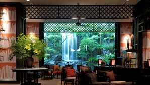 A room with a waterfall view, wooden furniture, and a large potted plant. - Urban Villa Konaya Hotel (Kofu)