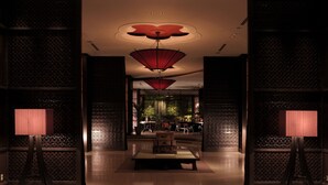 A lobby with a traditional design, featuring a central seating area, patterned walls, and a unique ceiling light fixture. - Urban Villa Konaya Hotel (Kofu)