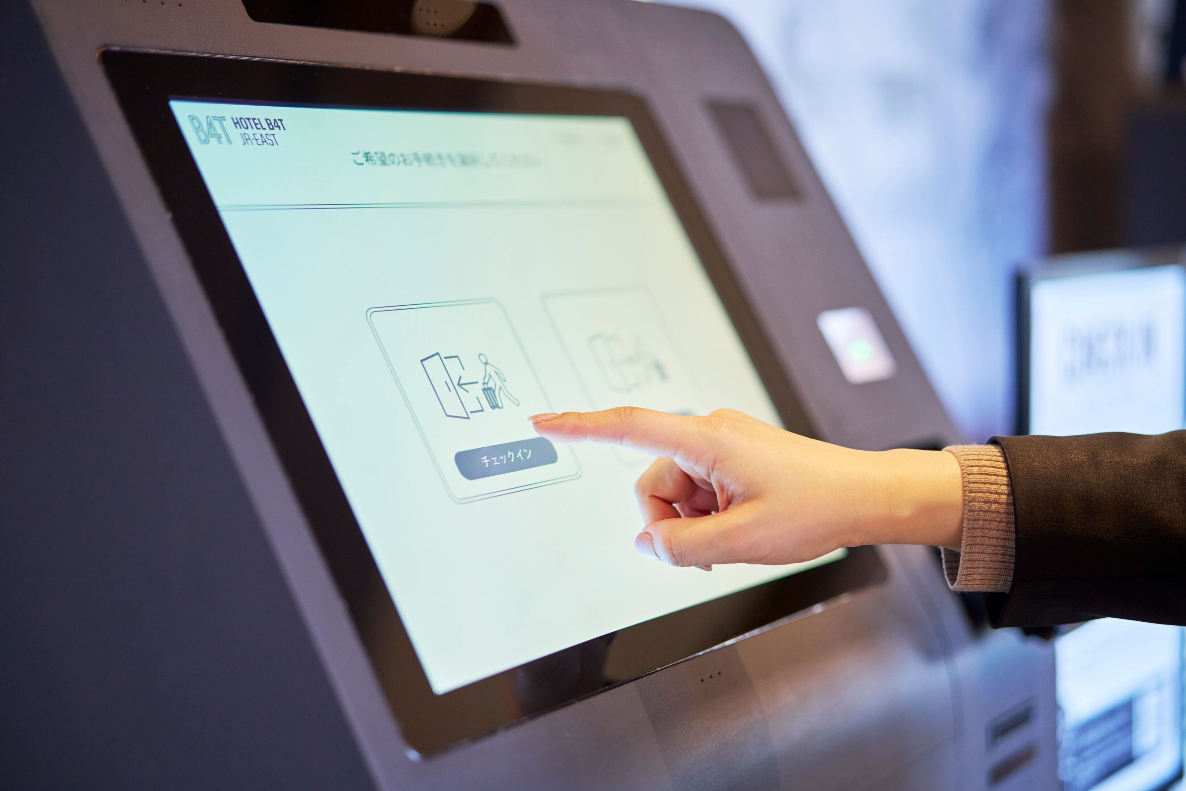 Une personne utilisant un kiosque numérique, peut-être pour s’enregistrer à l’hôtel ou pour obtenir des informations.