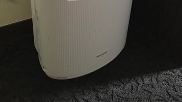 A white, cylindrical, compact appliance with a digital display and a blue light indicator, possibly a water heater or similar device.