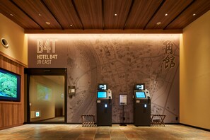A hotel reception area with a wooden ceiling, a map mural, and two check-in kiosks. - ホテルB4T角館 (Senboku)