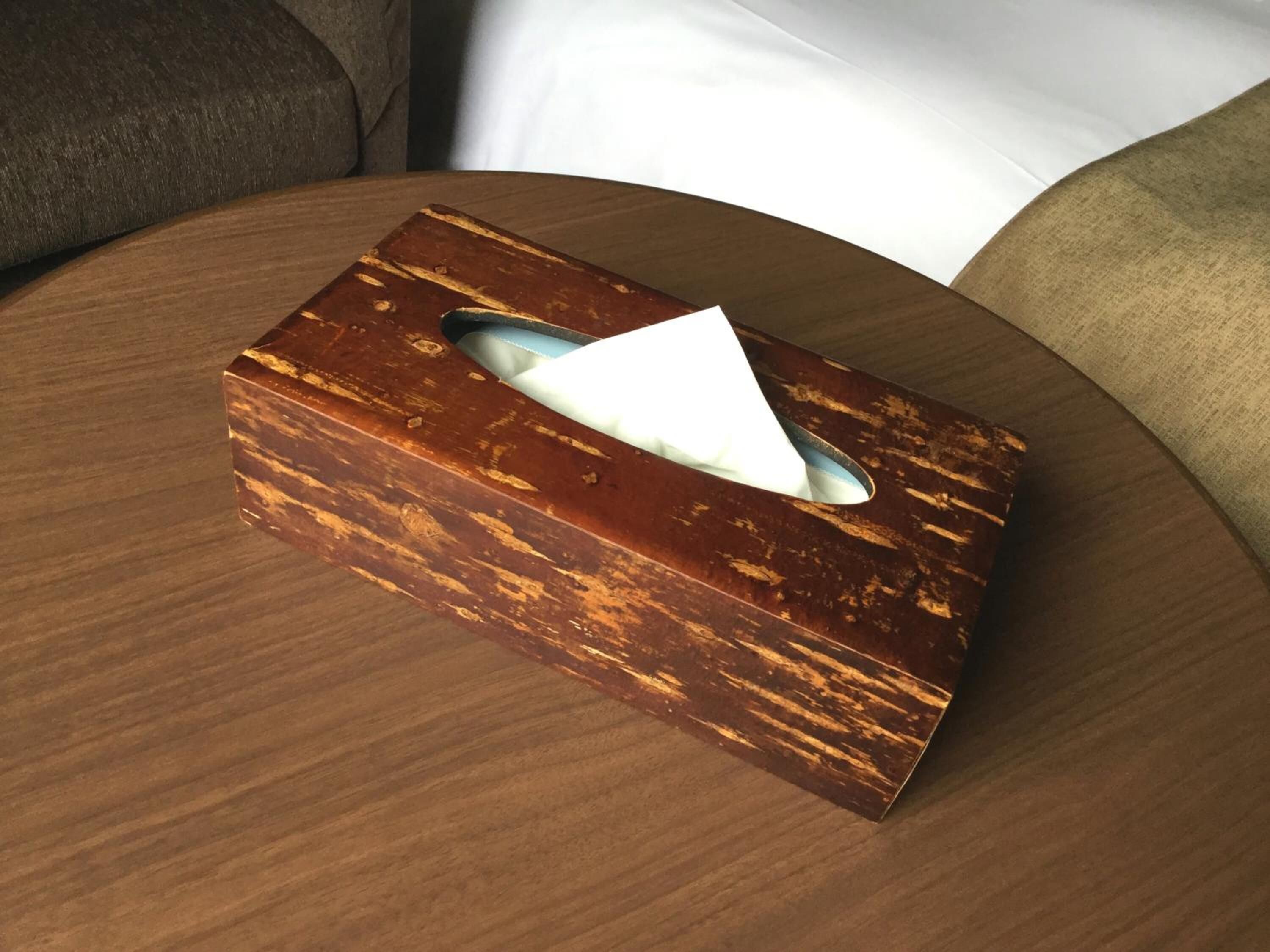 A wooden tissue box on a round wooden table.