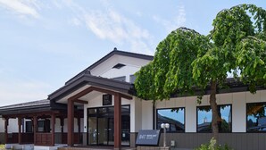 A hotel entrance with a traditional and modern architectural style, a signboard, and a tree in the foreground. - ホテルB4T角館 (Senboku)
