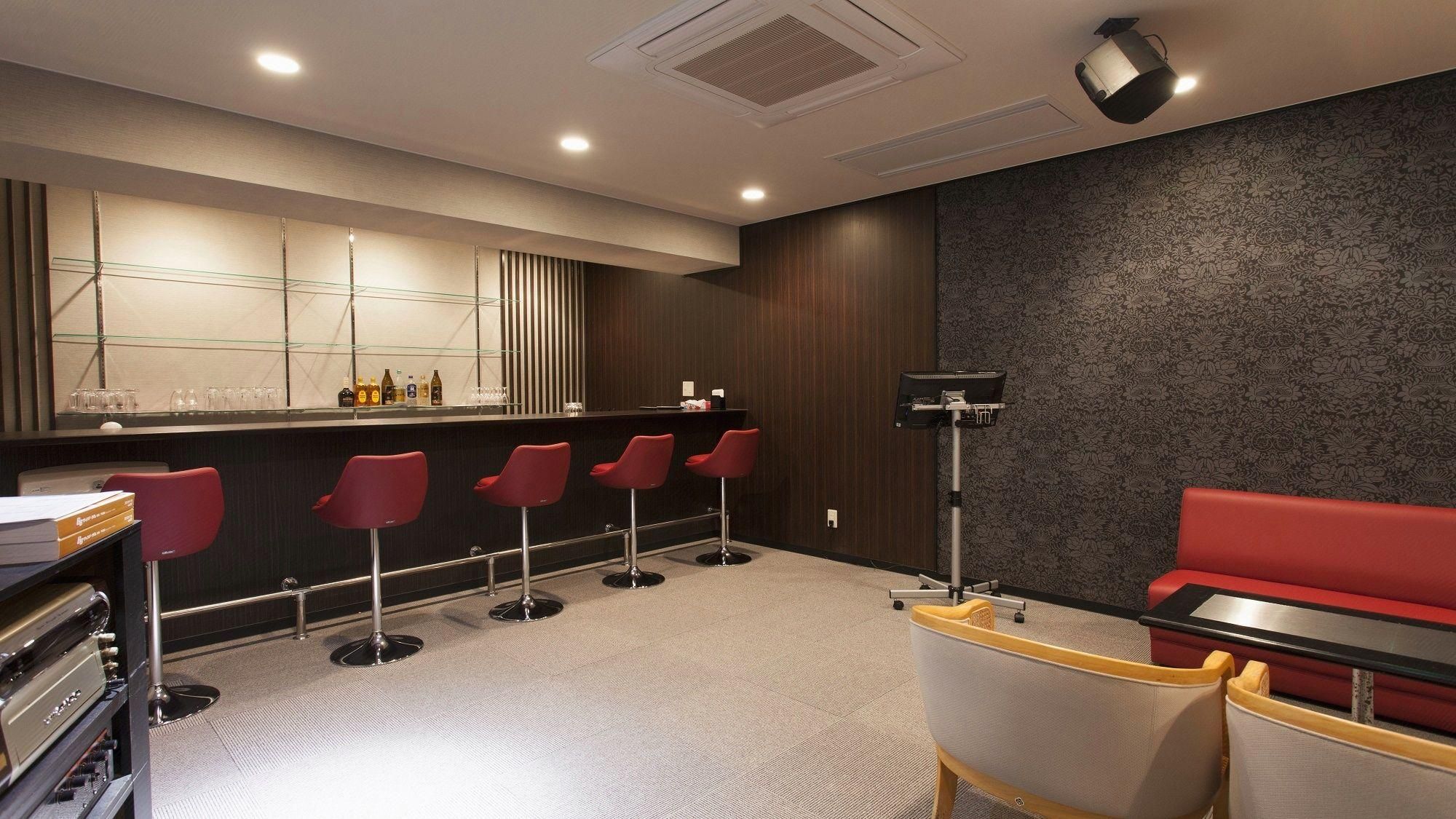 A bar area with a counter, stools, and a red couch.