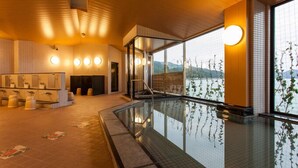 Une piscine intérieure moderne, dotée d’une paroi en verre, d’un espace sauna avec des bancs et offrant une vue sur un lac grâce à de grandes fenêtres.