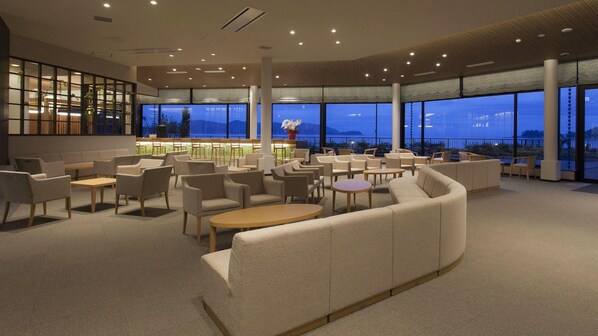 Een moderne lounge met zitplaatsen en een bar, grote ramen met uitzicht en een kamerbreed tapijt.