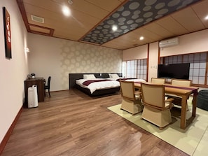 A hotel room with a bed, a desk, chairs, a TV, and a wooden floor. - Hotel Excel Kikusui (Nikaho)