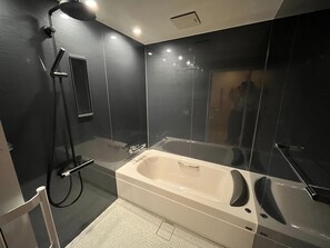 A modern bathroom with a large bathtub, a shower area, and a glass-enclosed shower stall. - Hotel Excel Kikusui (Nikaho)