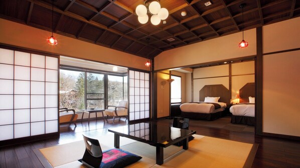 A traditional Japanese-style room with tatami flooring, a low table, and a bed with a wooden headboard. - Tsuta Onsen Ryokan (Towada)