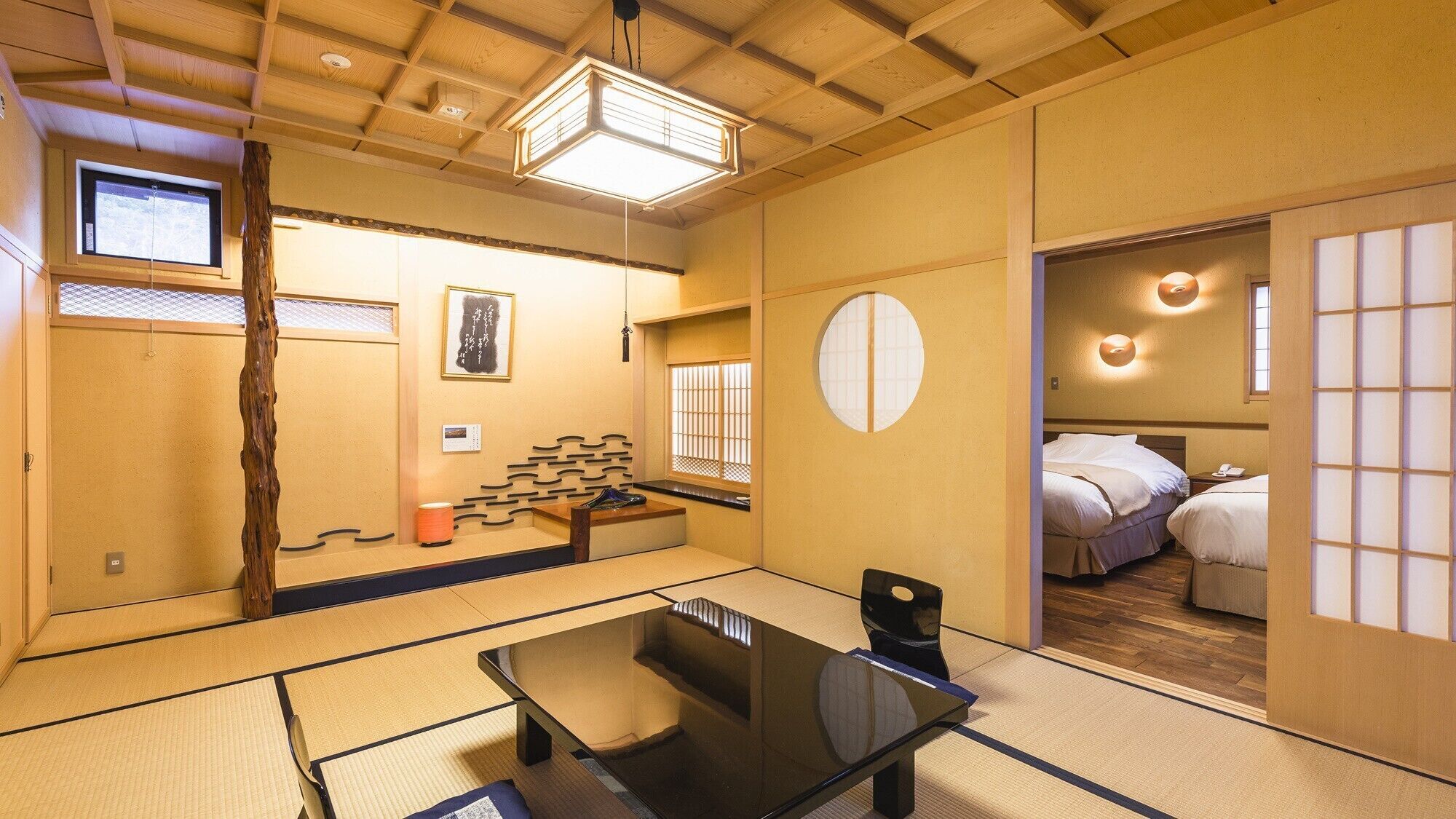 A traditional Japanese room with tatami flooring, a low table, a bed with futon bedding, and a sliding door.
