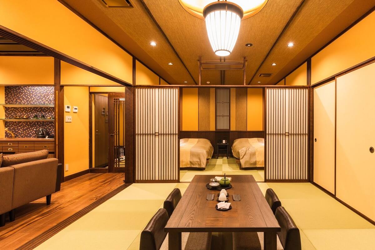 Una habitación japonesa tradicional con suelo de tatami, una mesa baja con un juego de té y puertas correderas.