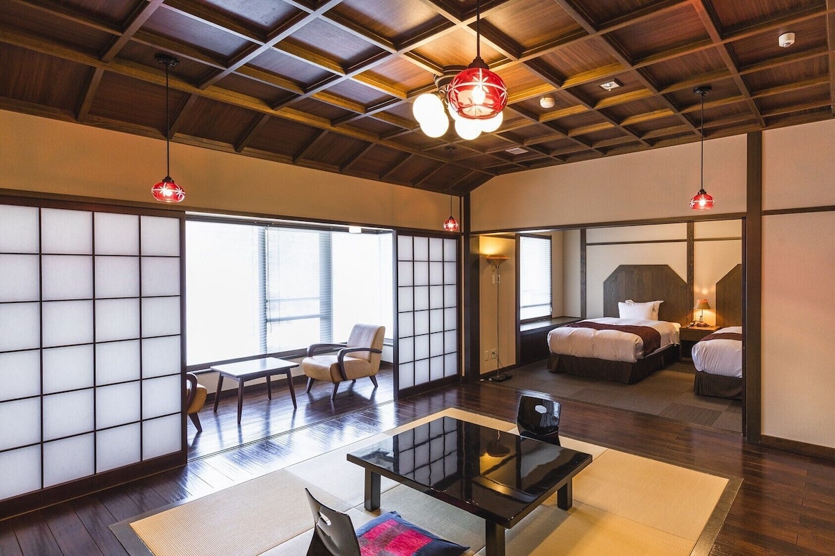 Una habitación tradicional japonesa con suelo de tatami, techo de madera bajo y puertas correderas shoji.