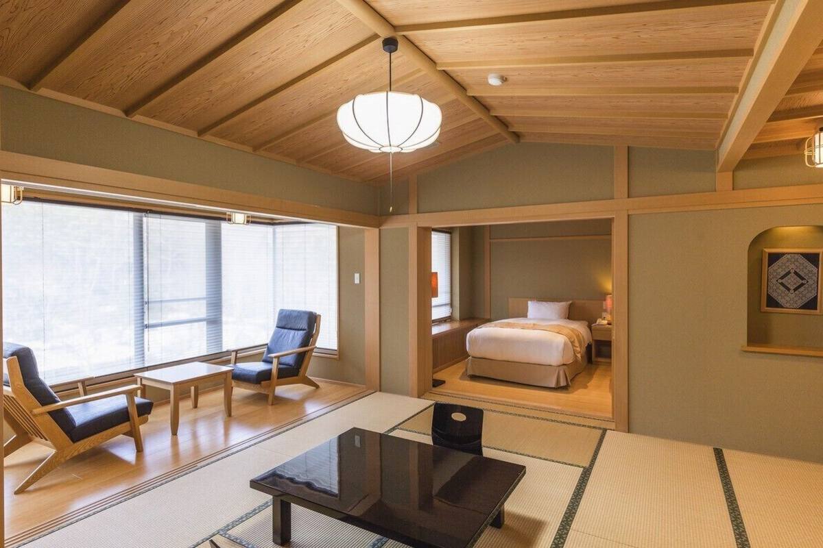 Una habitación tradicional japonesa con suelo de tatami, una cama baja, un escritorio y una silla.