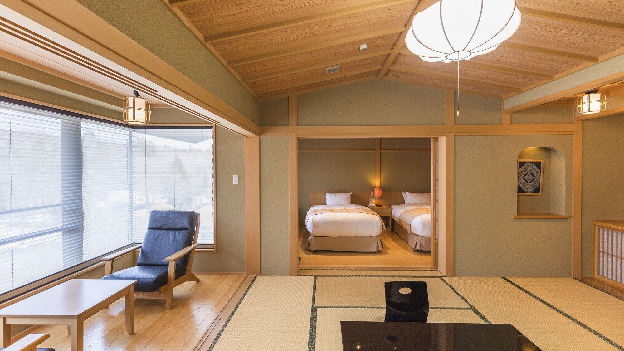 A hotel room with a large window, a wooden ceiling, a bed, a bedside table, and a chair.