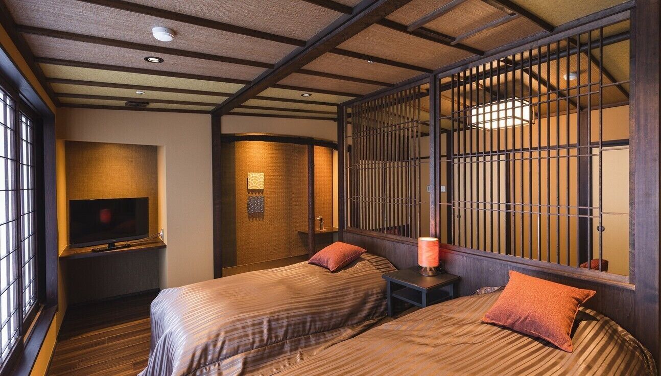 A traditional Japanese room with tatami flooring, a sliding door, and a television on a low stand.