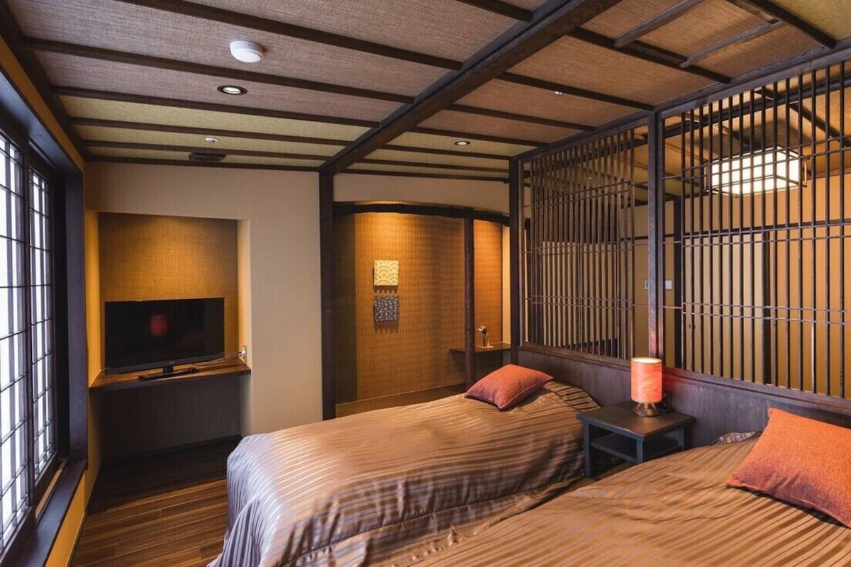 A traditional Japanese room with tatami flooring, a sliding door, and a television on a low stand.