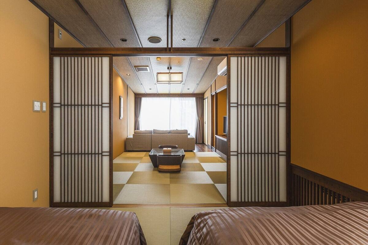 Una habitación tradicional japonesa con suelo de tatami, una mesa baja y puertas correderas.