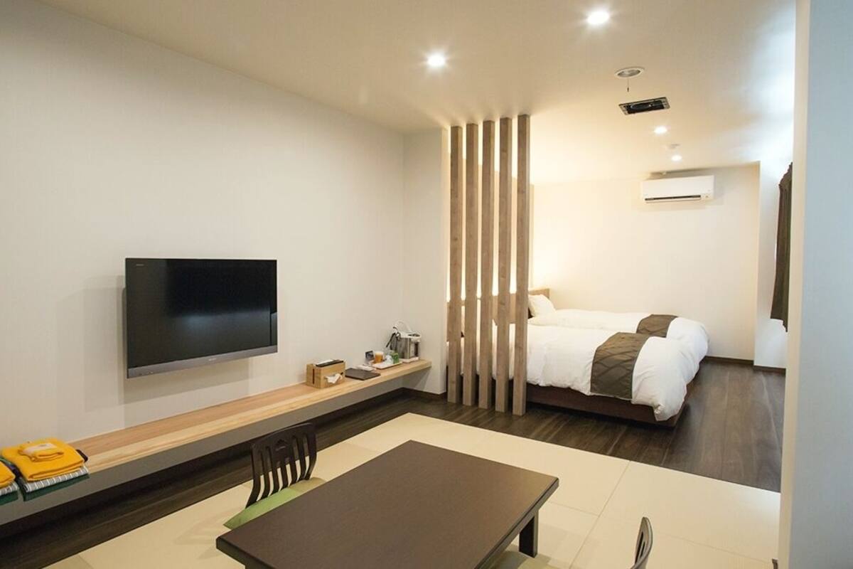Une chambre d’hôtel moderne équipée d’un téléviseur à écran plat, d’un lit, d’une table à manger et d’un canapé.