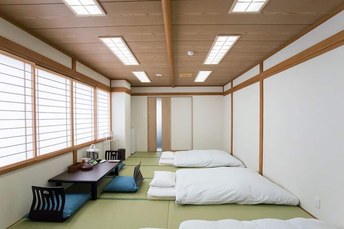 Une pièce de style japonais traditionnel, avec un sol recouvert de tatamis, une table basse avec des coussins et des futons servant de lits.