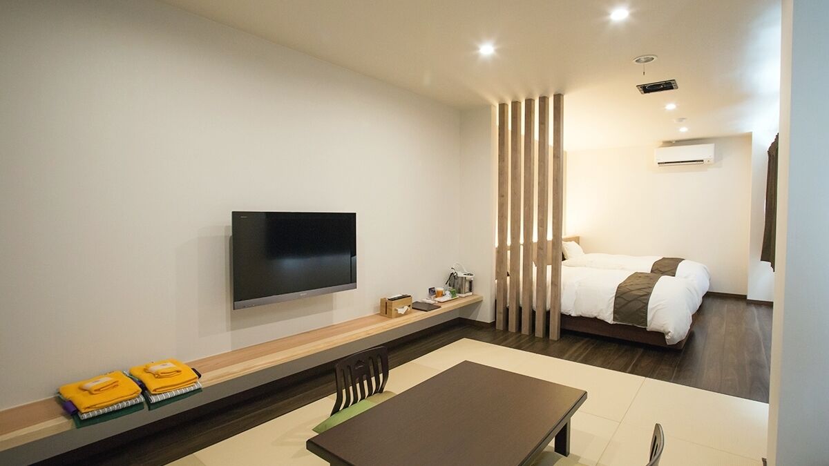 Een moderne hotelkamer met een flatscreen televisie, een bed, een eettafel en een zithoek.