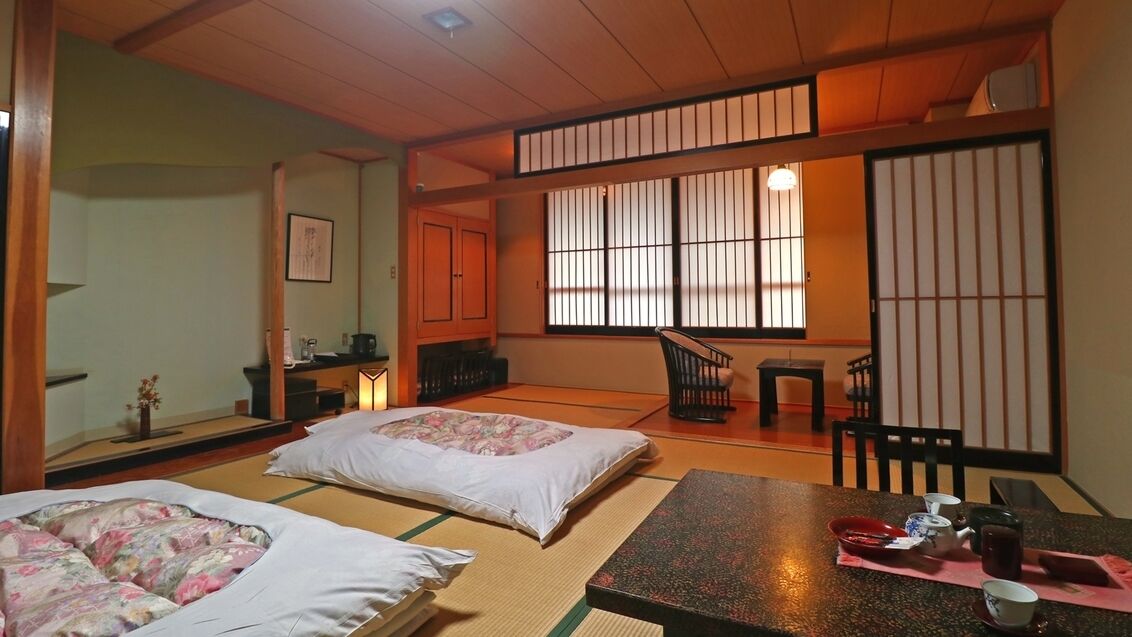 A traditional Japanese room with tatami flooring, a low table with tea set, and sliding doors.