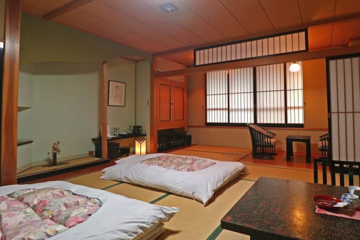 Une pièce de style japonais traditionnel, avec un sol recouvert de tatamis, une petite table basse accompagnée d’un service à thé et des portes coulissantes.