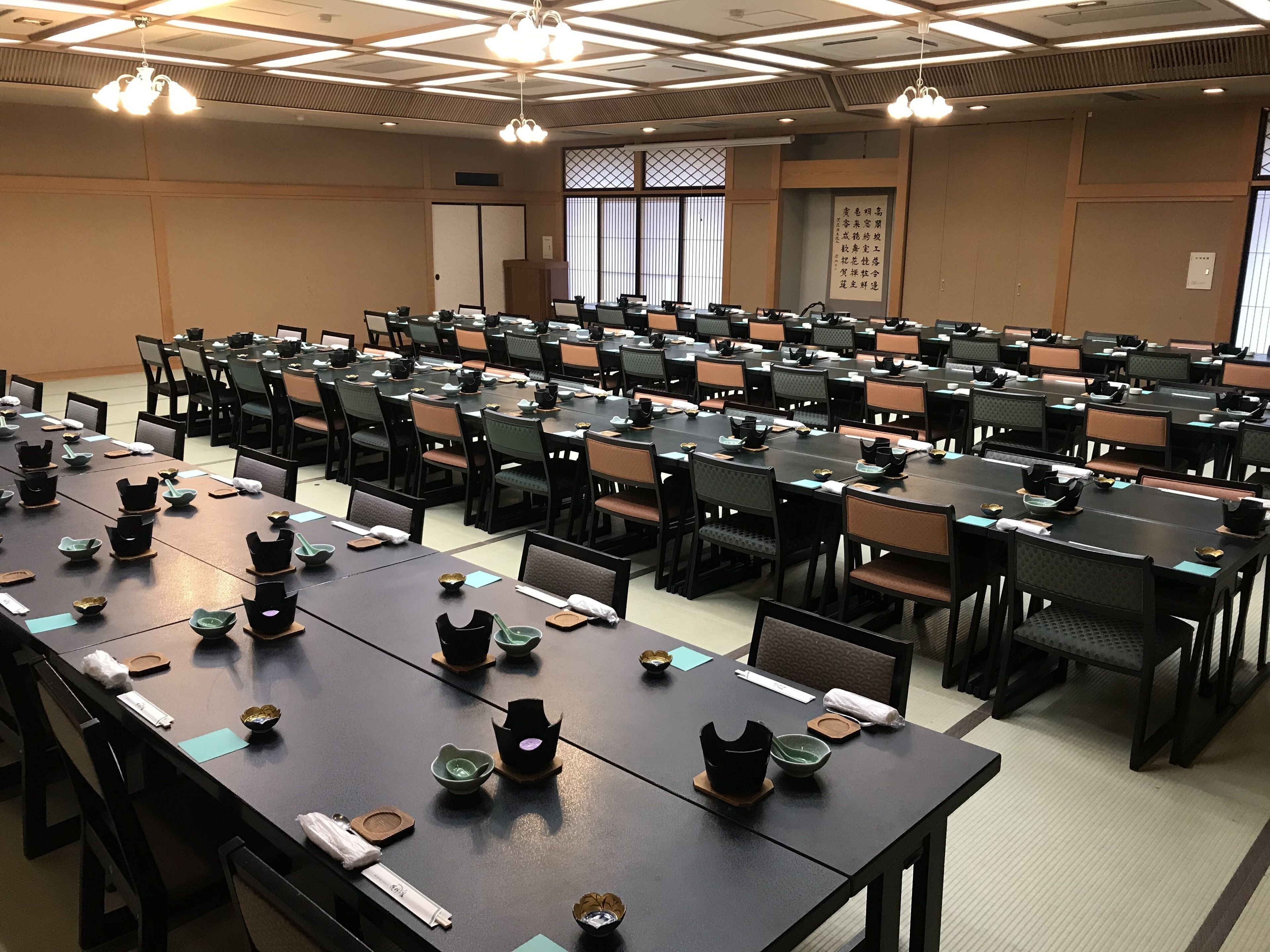 A conference room with multiple tables and chairs, equipped with nameplates and table settings.