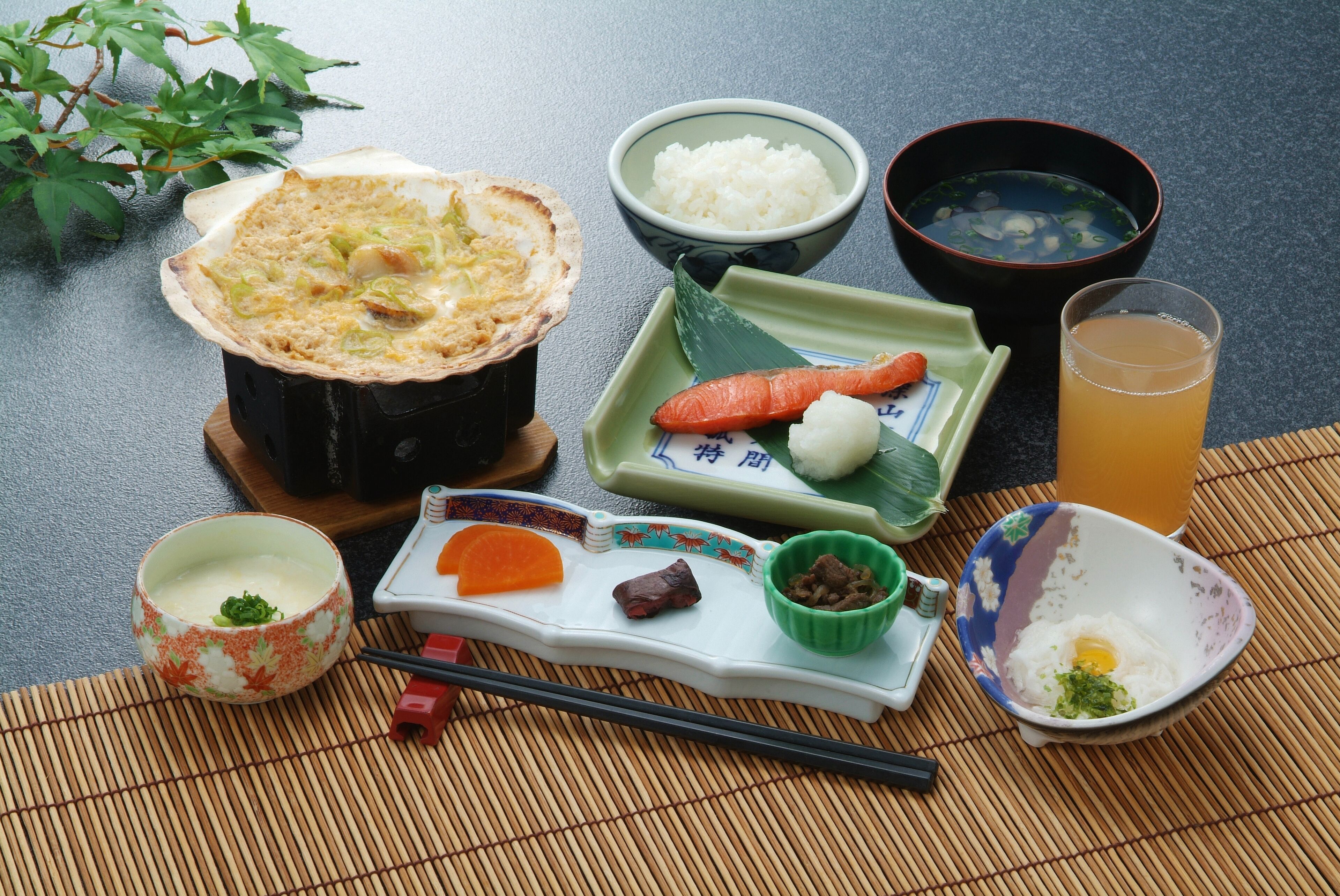 A traditional Japanese meal setup with rice, soup, and various side dishes on a table.