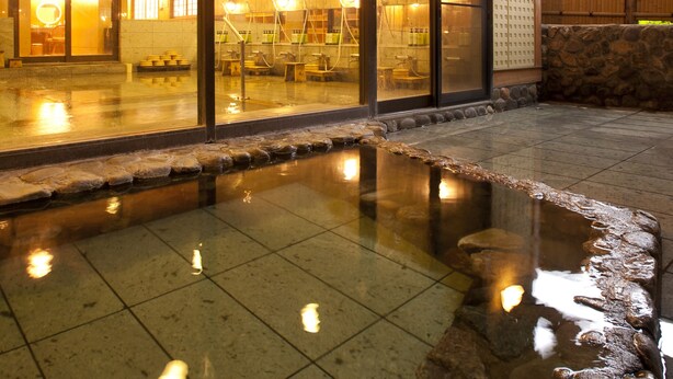 A traditional Japanese onsen with a stone bath, wooden beams, and a tiled floor. - Kazennosyo (Kuroishi)