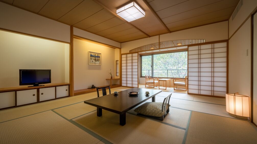 A traditional Japanese room with tatami flooring, a low table, a television, and sliding doors.
