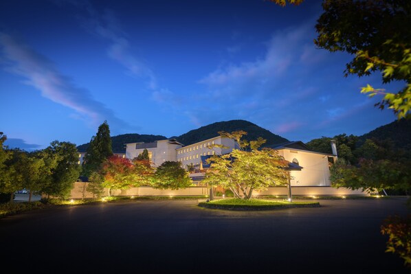 A large, modern hotel with a symmetrical facade, surrounded by lush greenery and a mountain backdrop. - Surikamitei Ohtori (Fukushima)