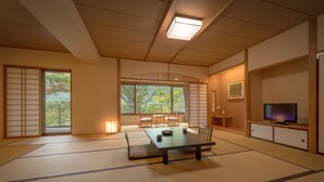 A traditional Japanese room with tatami flooring, a low table with cushions, sliding doors, and a television. - Surikamitei Ohtori (Fukushima)