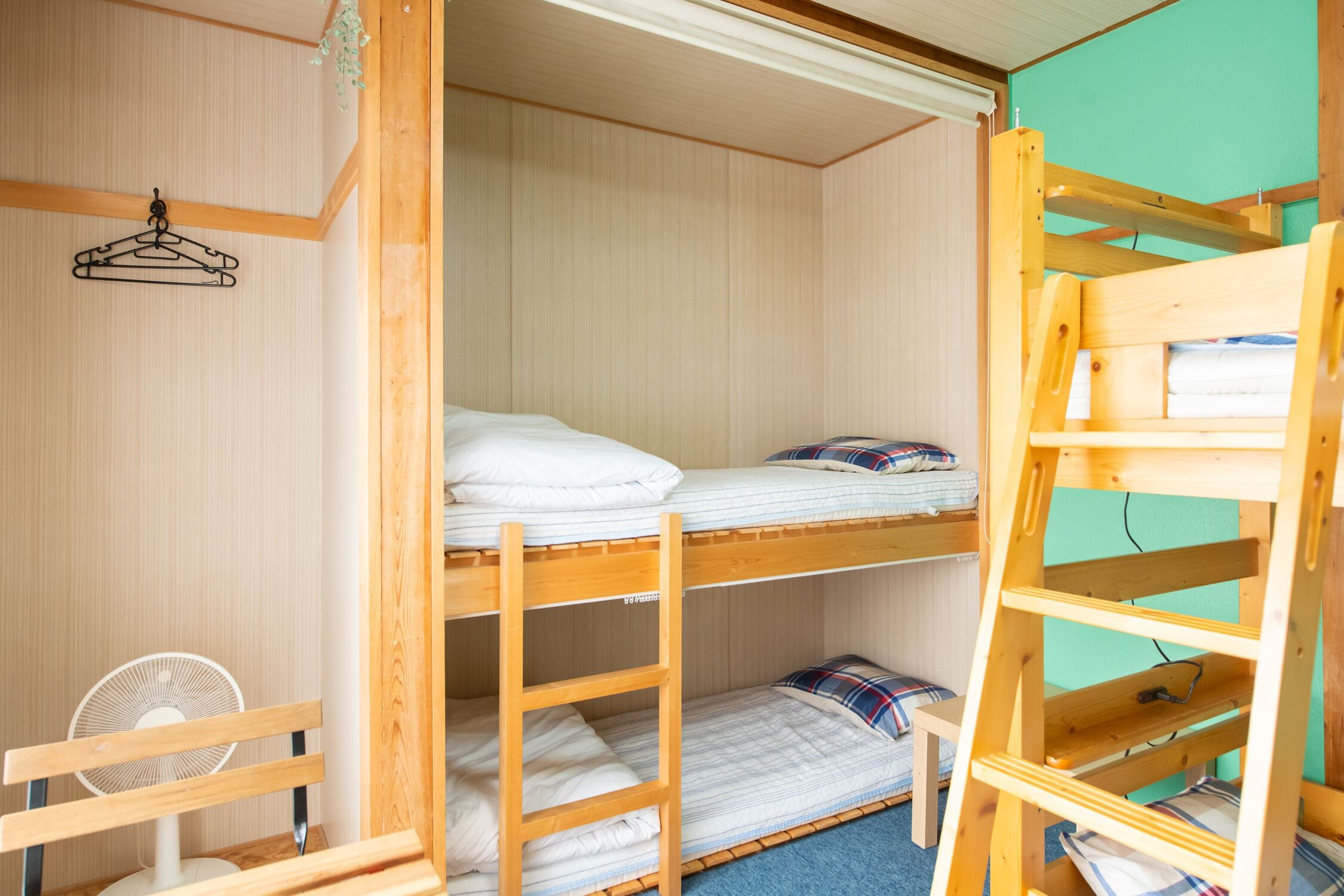 A bunk bed room with a wooden ladder and a small table.