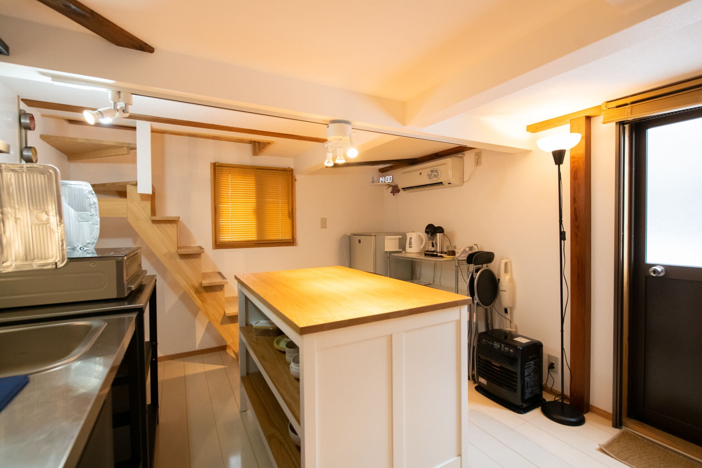 Una cocina compacta con encimera de madera, estantes empotrados, un refrigerador, un microondas y una cafetera.