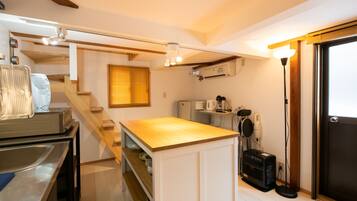 Una cocina compacta con encimera de madera, estantes empotrados, un refrigerador, un microondas y una cafetera.