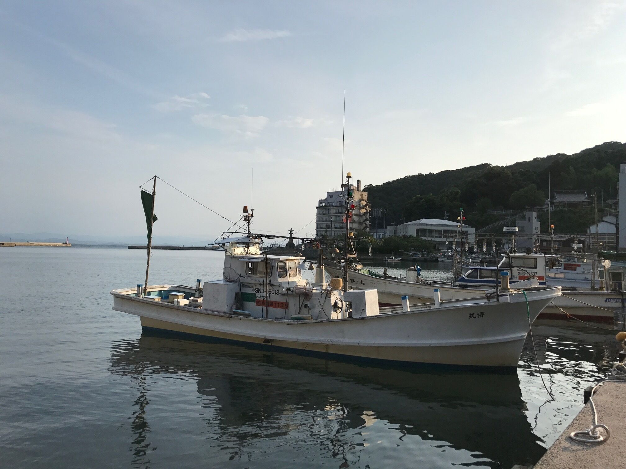 A boat docked at a harbor with a building in the background.