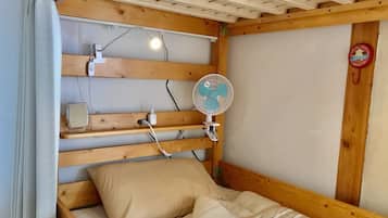 A wooden bunk bed with a headboard, a bedside table, a fan, and a wall-mounted clock.