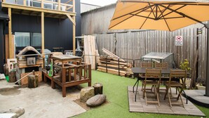 A backyard with a wooden deck, a barbecue grill, and a dining table with chairs. - Destiny Inn Sakaiminato (Sakaiminato)
