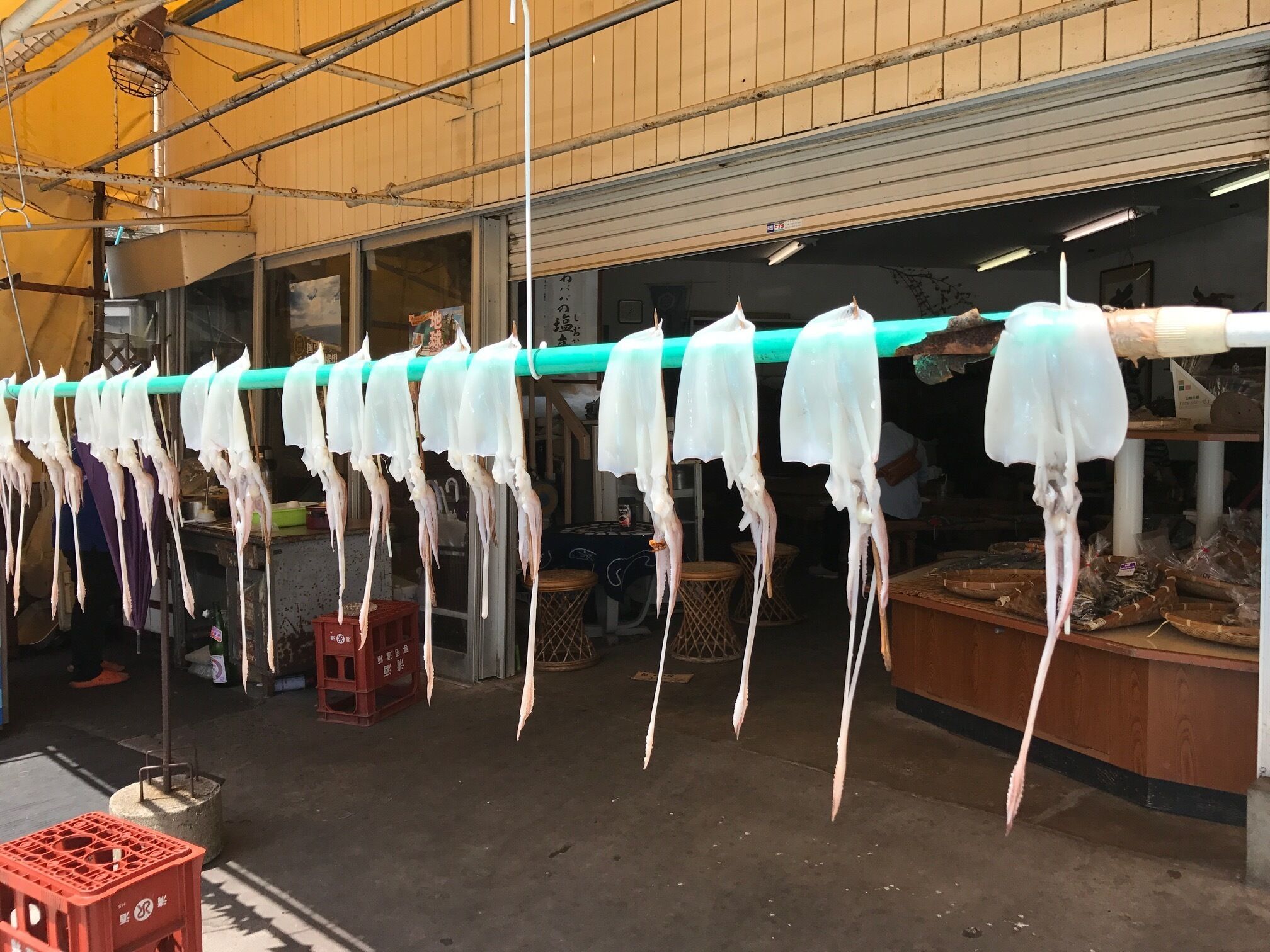Een straatbeeld met een rij witte plastic zakken aan een groene paal voor een gebouw.