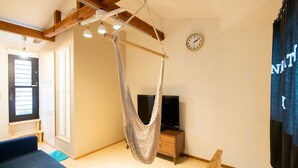 A room with a hanging chair, a bed, a TV, and a clock on the wall. - Destiny Inn Sakaiminato (Sakaiminato)
