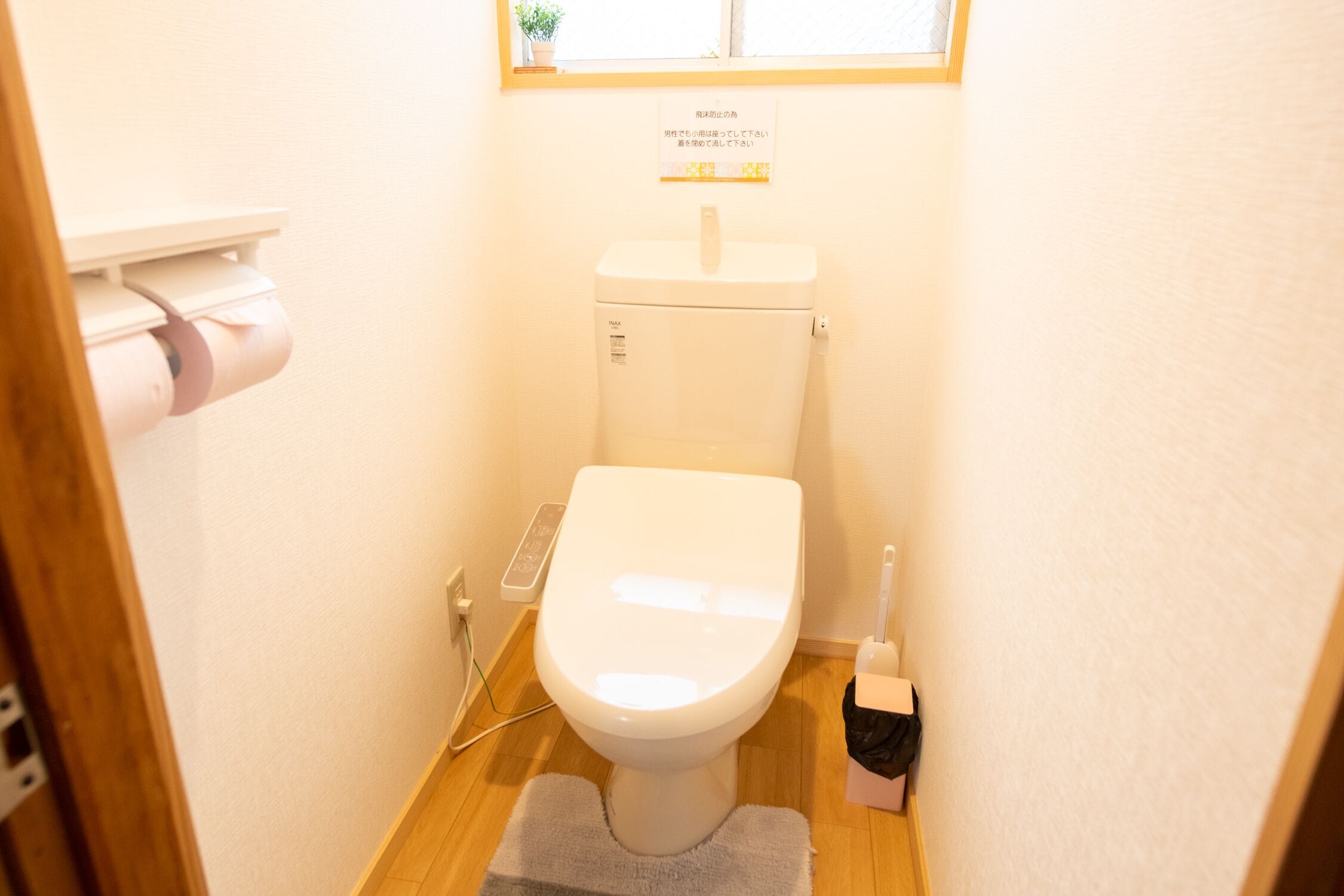 A small bathroom with a toilet, a toilet paper holder, and a bidet.
