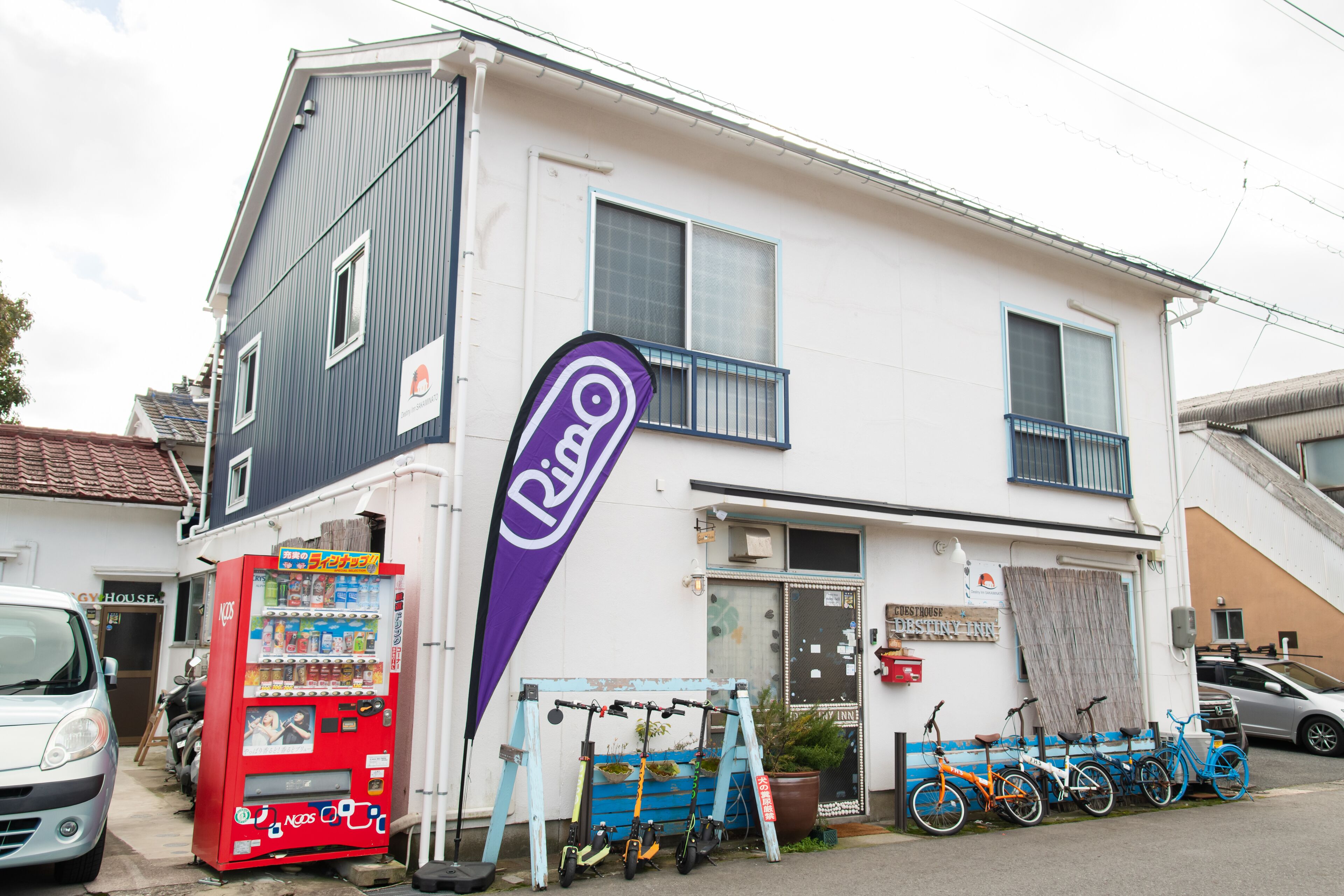 Un bâtiment à deux étages, avec un distributeur automatique, des vélos et une enseigne indiquant un restaurant.