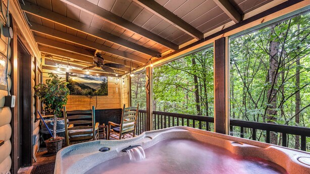 A hot tub with a wooden deck, a ceiling fan, and a view of a forest. - Twilight Point Pet Friendly! Book NOW and receive tickets to Dollywood, Anakeesta and many more (Gatlinburg)