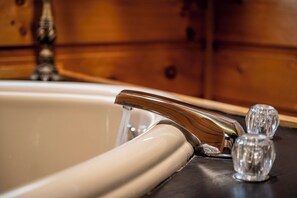 A bathtub with a chrome faucet and two clear glass bottles on the side.