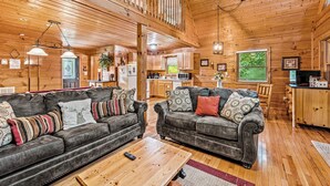A cozy cabin interior with a wooden ceiling, two leather sofas with patterned cushions, a wooden dining table, and a kitchen area. - Twilight Point Pet Friendly! Book NOW and receive tickets to Dollywood, Anakeesta and many more (Gatlinburg)