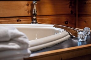 A bathroom with a wooden vanity, a white sink, and a decorative faucet.