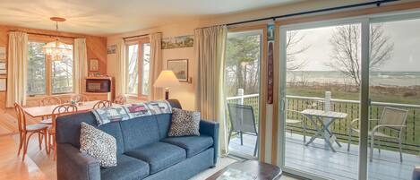 A living room with a sofa, coffee table, and a view of the outdoors through a sliding glass door.
