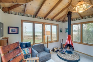 Una habitación acogedora con chimenea, ventanas amplias, un sillón cómodo y una estantería.