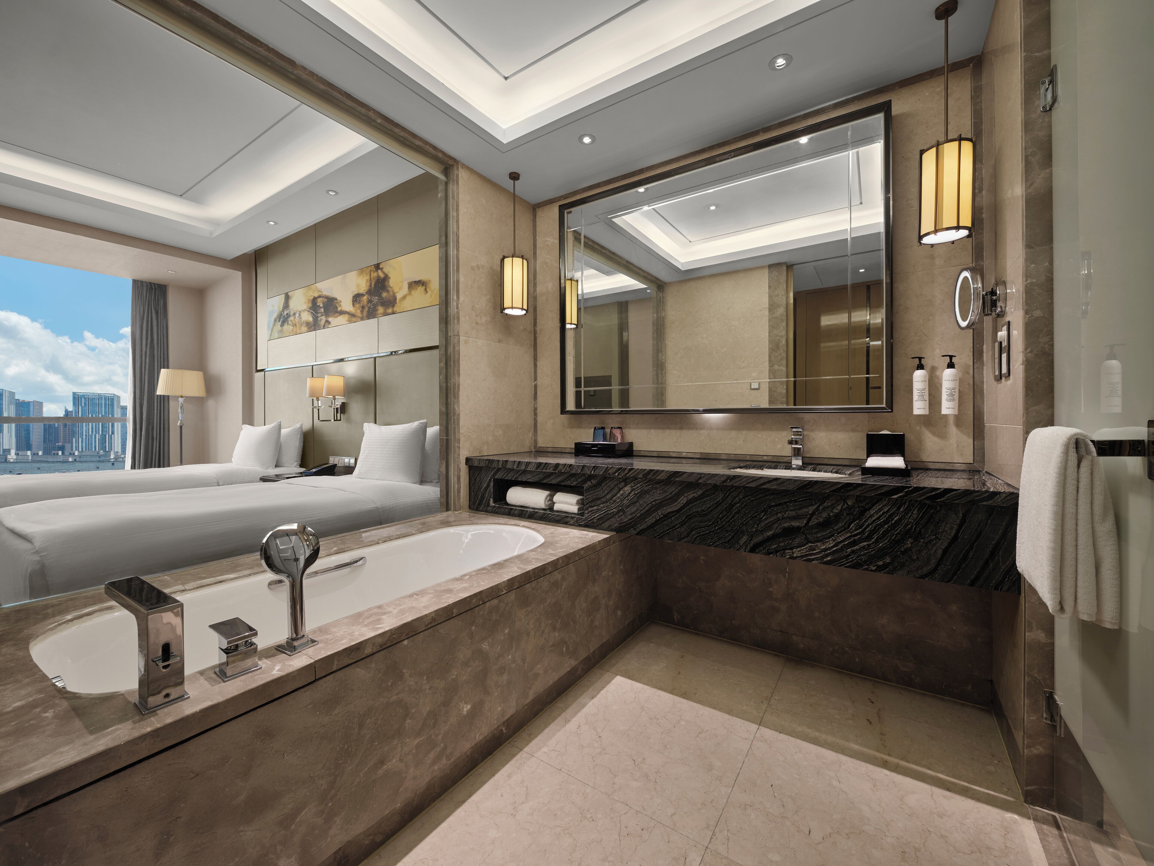 A modern hotel bathroom with a large bathtub, a separate shower area, and a large mirror.